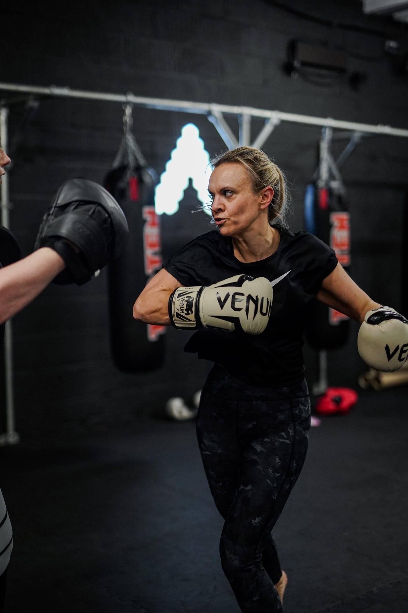 An Apex member training in boxing stance, lit by the academy's signature wall light.