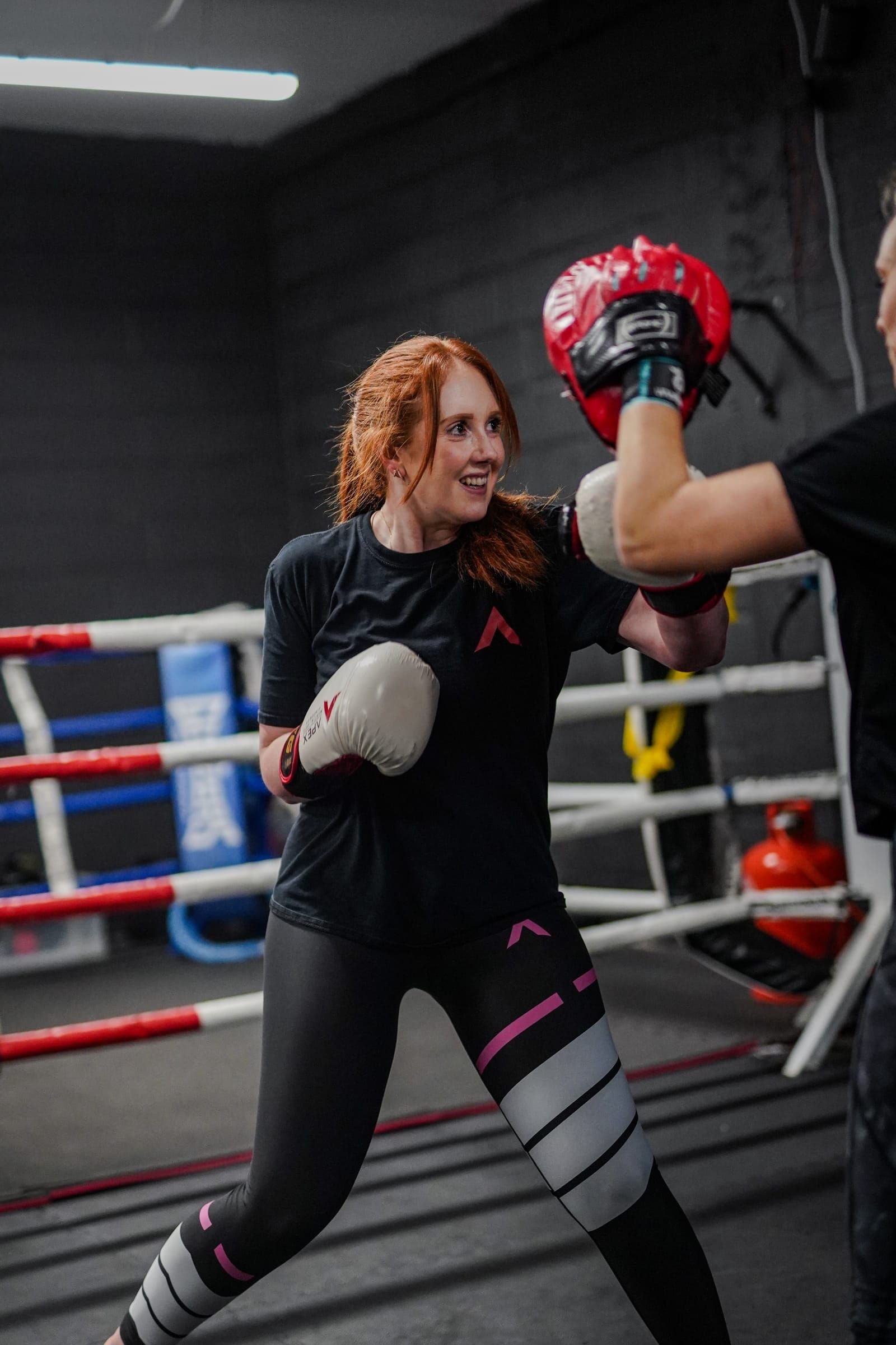 Member smiling in the boxing ring after a class at Apex.