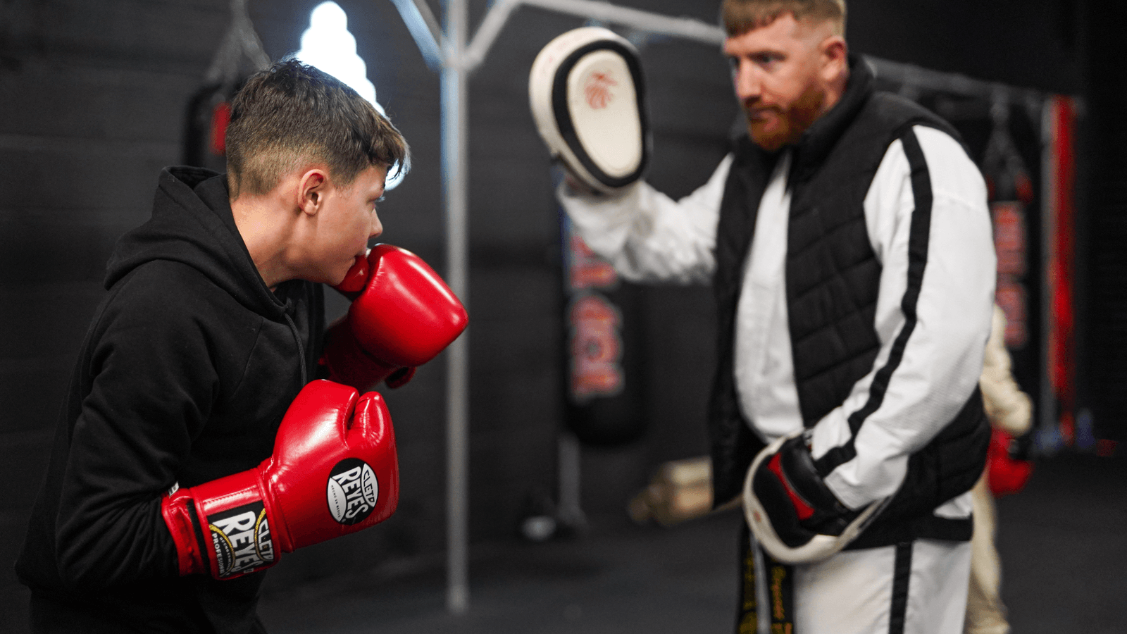 A junior boxer working pads with an Apex coach.